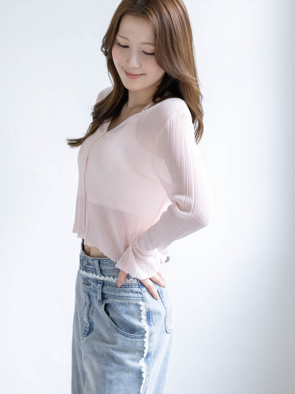 ブルー系のデニムパンツ、ホワイト系のパンプス、ピンク系のカーディガン/ボレロを着用したレディースの春コーディネートの4枚目の写真