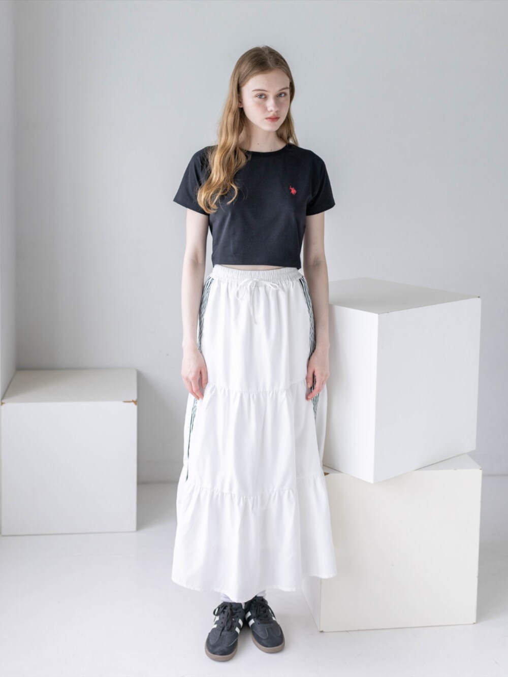 ブラック系のスニーカー、ホワイト系のスカート、ブラック系のTシャツ/カットソーを着用したレディースの夏コーディネートの3枚目の写真