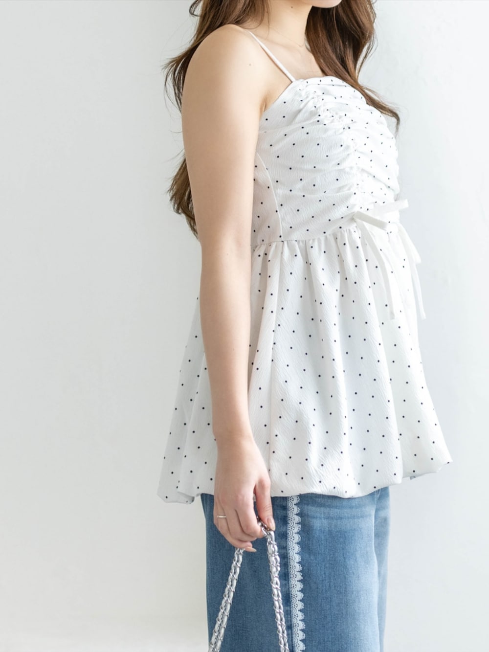 シルバー系のパンプス、ホワイト系のチュニック、ブルー系のデニムパンツを着用したレディースの春コーディネートの4枚目の写真