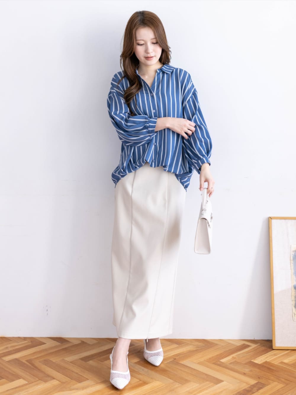 ホワイト系のスカート、ブルー系のシャツ/ブラウス、ホワイト系のパンプスを着用したレディースの夏コーディネートの2枚目の写真