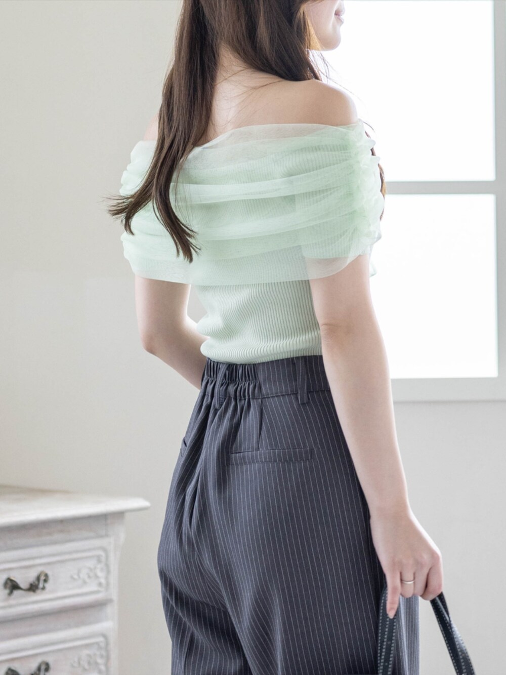 ブラック系のボストンバッグ、ブラック系のパンプス、グレー系のスラックスを着用したレディースの春コーディネートの5枚目の写真