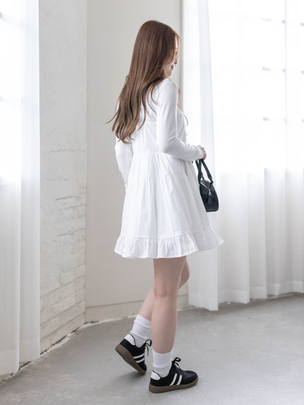 ブラック系のスニーカー、ホワイト系のTシャツ/カットソー、ホワイト系のワンピースを着用したレディースの春コーディネートの6枚目の写真