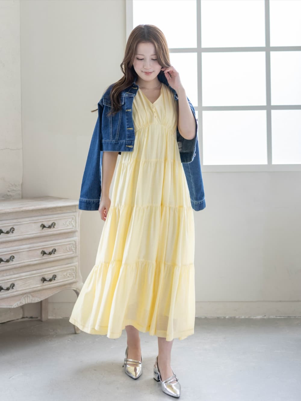 シルバー系のパンプス、ブルー系のデニムジャケット、イエロー系のワンピースを着用したレディースの春コーディネートの2枚目の写真