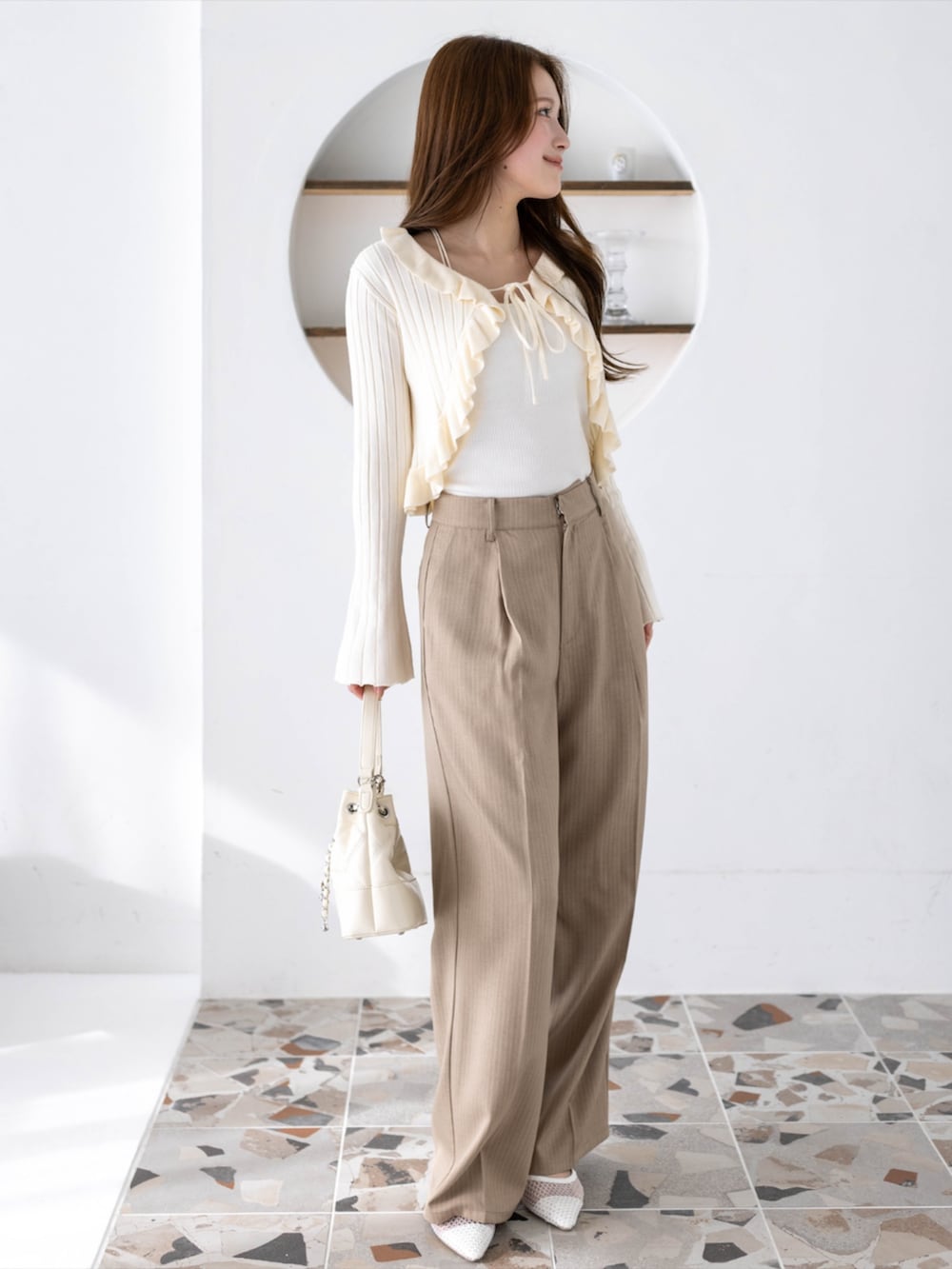 ベージュ系のその他パンツ、ホワイト系のカーディガン/ボレロ、ホワイト系のハンドバッグを着用したレディースの冬コーディネートの3枚目の写真