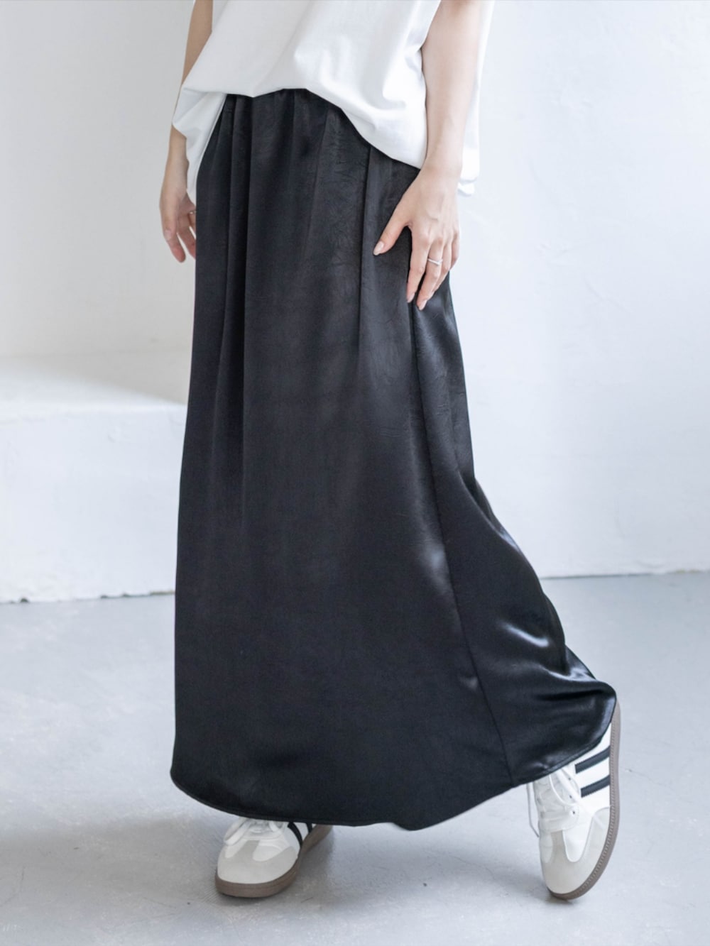 ホワイト系のスニーカー、ブラック系のスカート、ホワイト系のTシャツ/カットソーを着用したレディースの春コーディネートの6枚目の写真