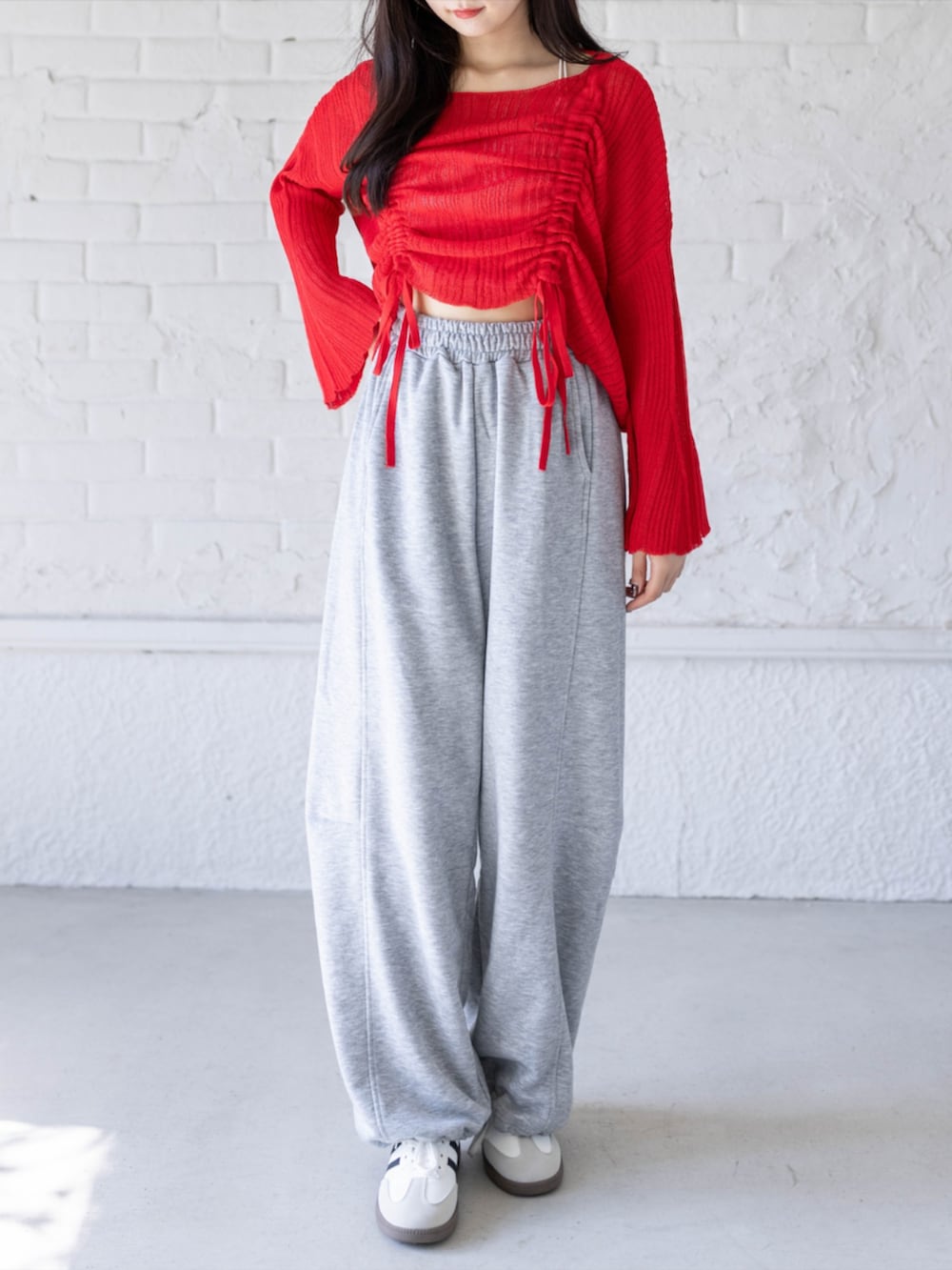 ホワイト系のスニーカー、グレー系のスウェットパンツ、レッド系のニット/セーターを着用したレディースの春コーディネートの2枚目の写真
