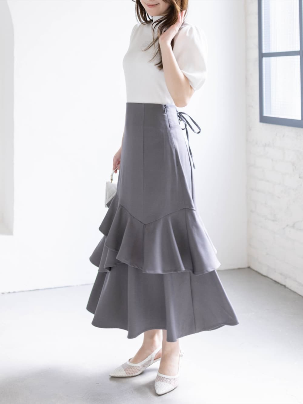ホワイト系のパンプス、ホワイト系のニット/セーター、グレー系のスカートを着用したレディースの春コーディネートの3枚目の写真