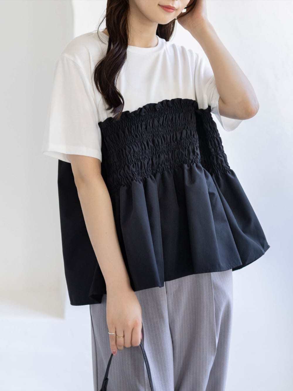 ブラック系のパンプス、グレー系のスラックス、ブラック系のハンドバッグを着用したレディースの夏コーディネートの7枚目の写真