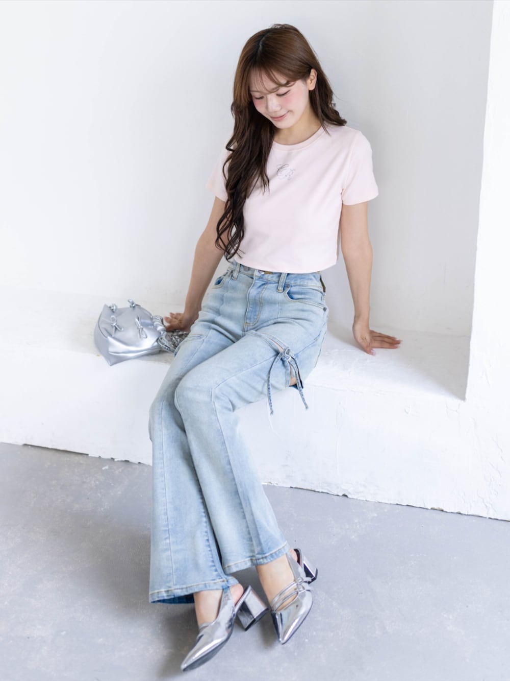 シルバー系のパンプス、ブルー系のデニムパンツ、ホワイト系のショルダーバッグを着用したレディースの夏コーディネートの5枚目の写真