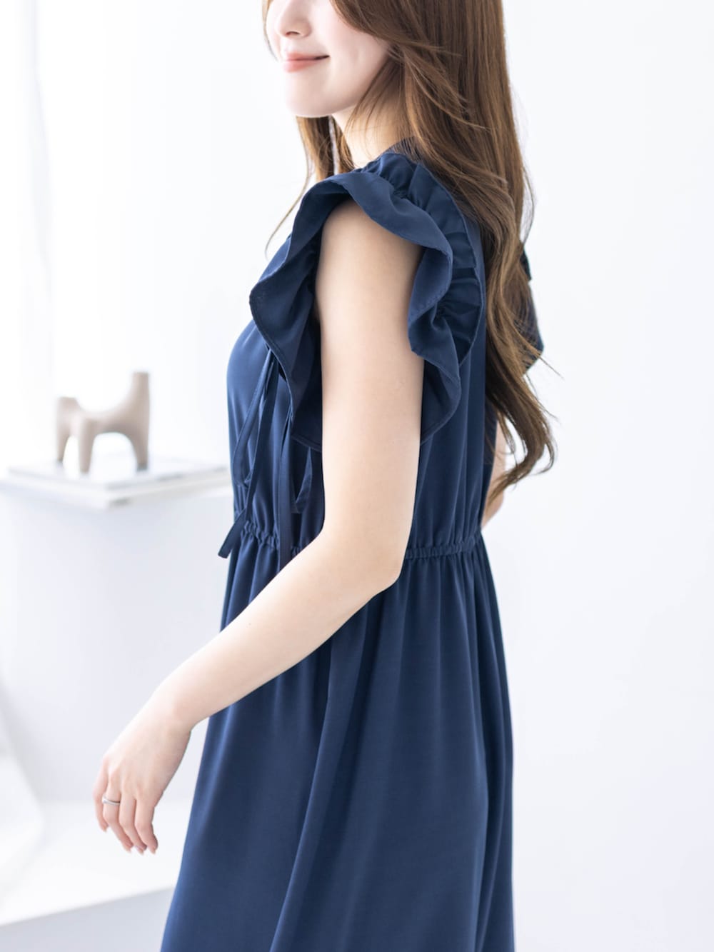 ブラック系のハンドバッグ、ブラック系のパンプス、ブルー系のワンピースを着用したレディースの春コーディネートの6枚目の写真