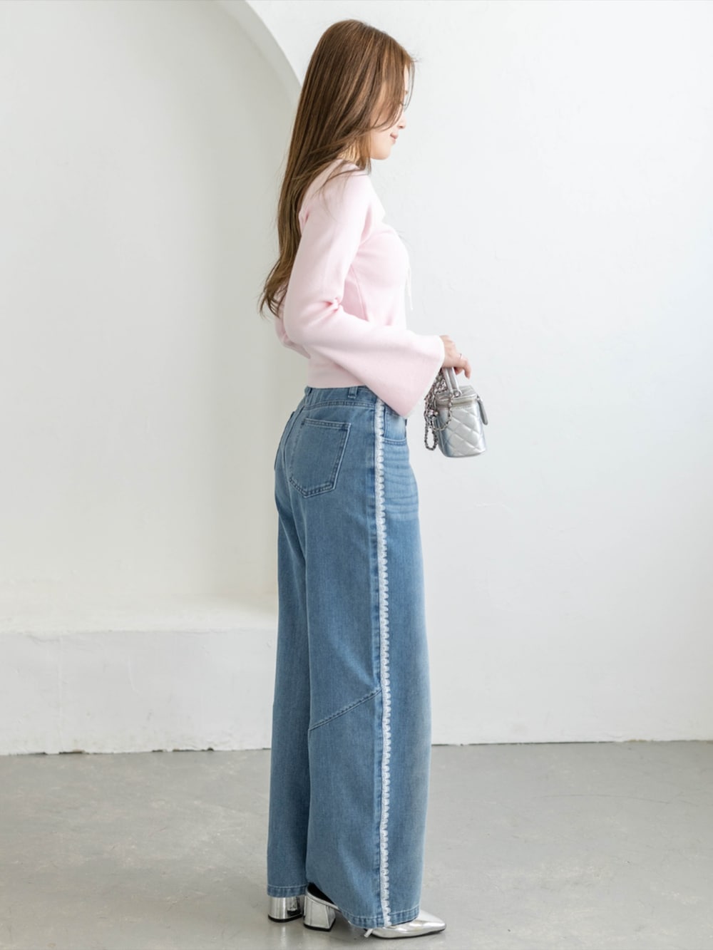 シルバー系のパンプス、ブルー系のデニムパンツ、ピンク系のニット/セーターを着用したレディースの冬コーディネートの3枚目の写真