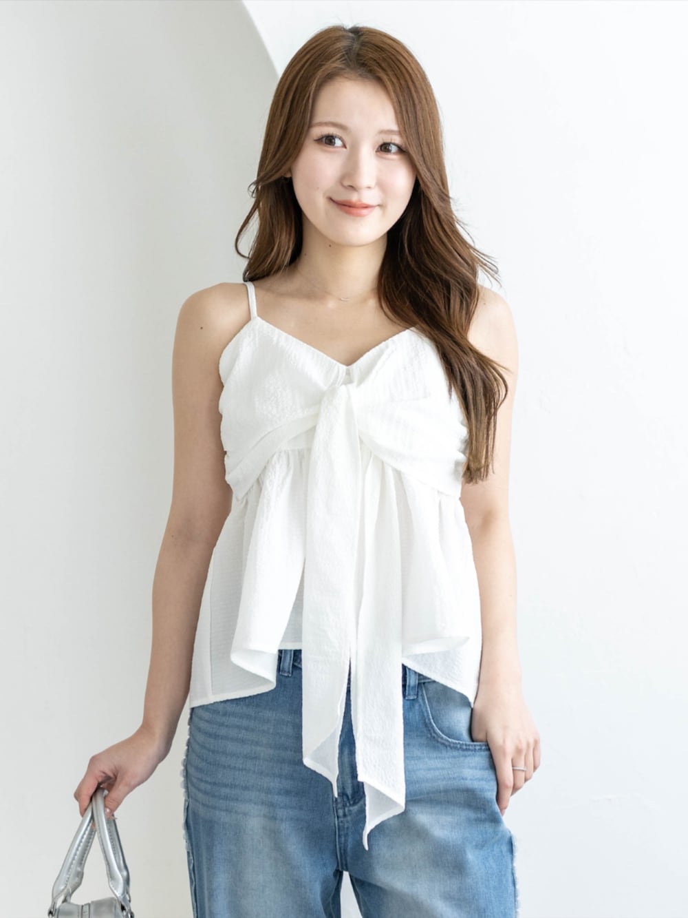 シルバー系のパンプス、ブルー系のデニムパンツ、ホワイト系のキャミソールを着用したレディースの夏コーディネートの4枚目の写真