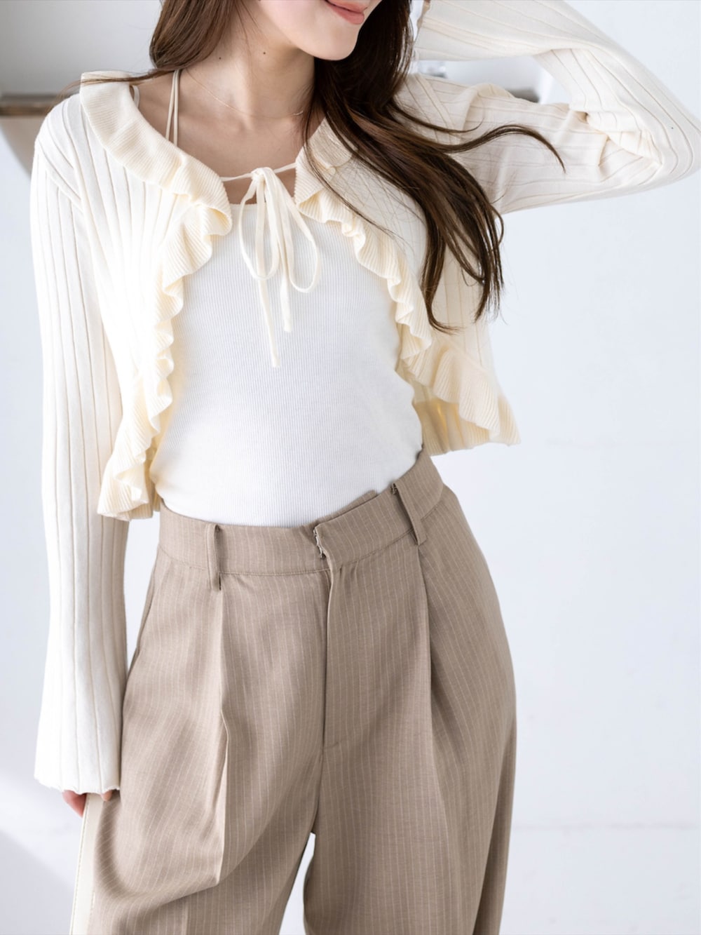 ベージュ系のその他パンツ、ホワイト系のカーディガン/ボレロ、ホワイト系のハンドバッグを着用したレディースの冬コーディネートの5枚目の写真