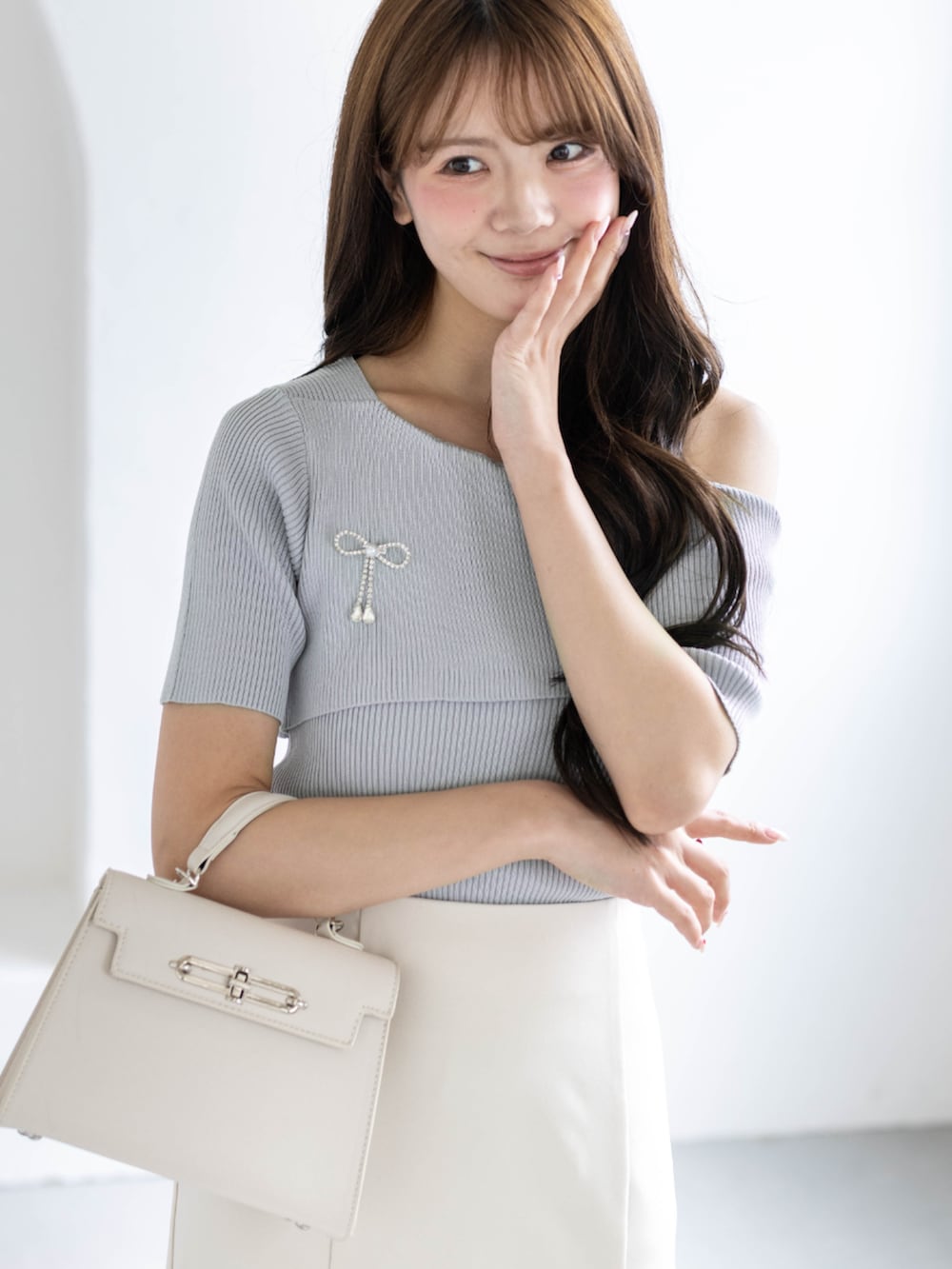 ホワイト系のスカート、ホワイト系のハンドバッグ、グレー系のニット/セーターを着用したレディースの春コーディネートの3枚目の写真