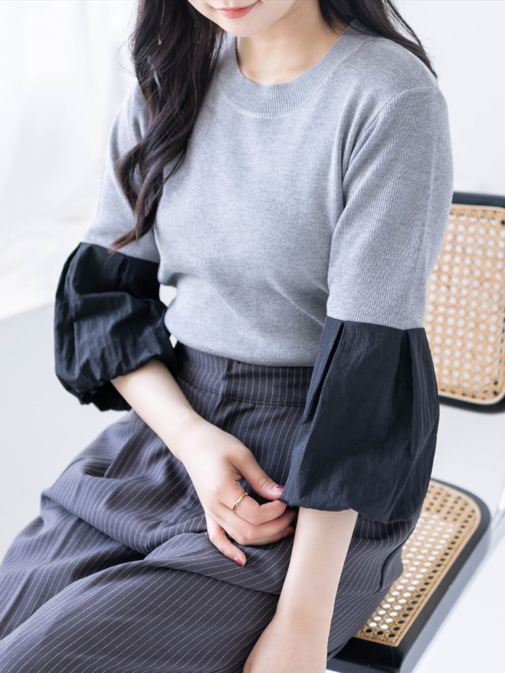 ブラック系のハンドバッグ、ブラック系のパンプス、グレー系のスラックスを着用したレディースの夏コーディネートの6枚目の写真