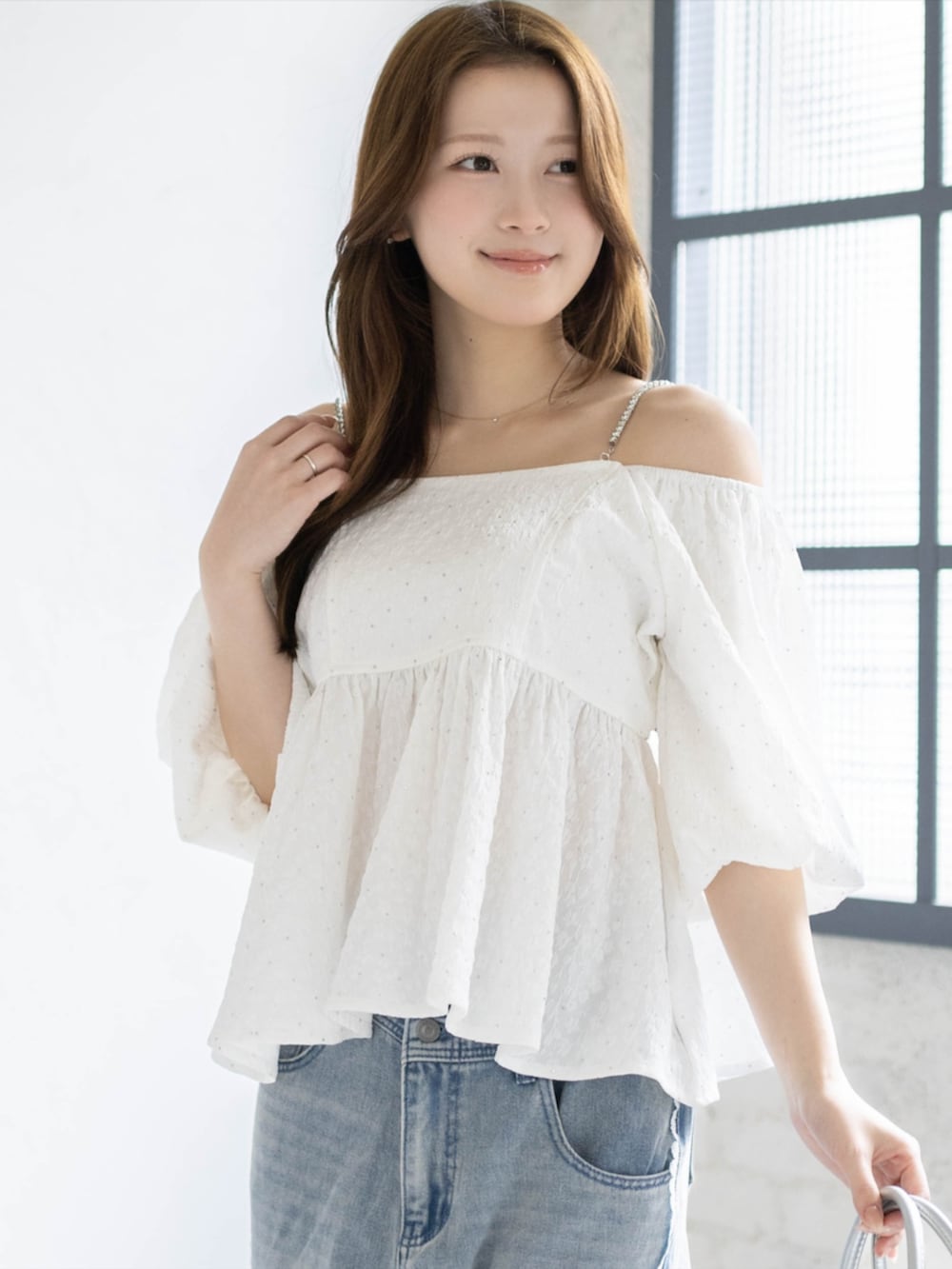 シルバー系のハンドバッグ、ブルー系のデニムパンツ、ホワイト系のパンプスを着用したレディースの春コーディネートの4枚目の写真