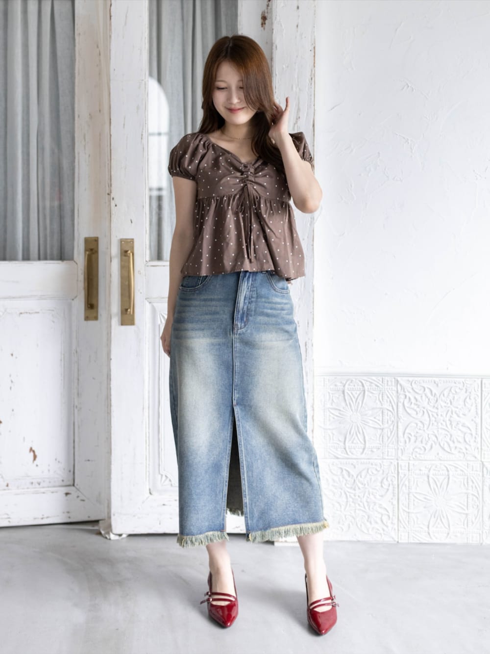 レッド系のパンプス、ブルー系のデニムスカート、ブラウン系のシャツ/ブラウスを着用したレディースの夏コーディネートの2枚目の写真