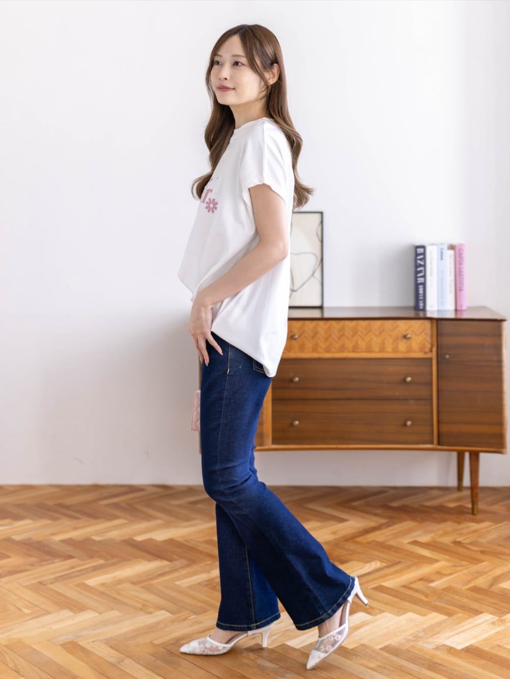 ブルー系のデニムパンツ、ホワイト系のパンプス、ホワイト系のTシャツ/カットソーを着用したレディースの春コーディネートの2枚目の写真