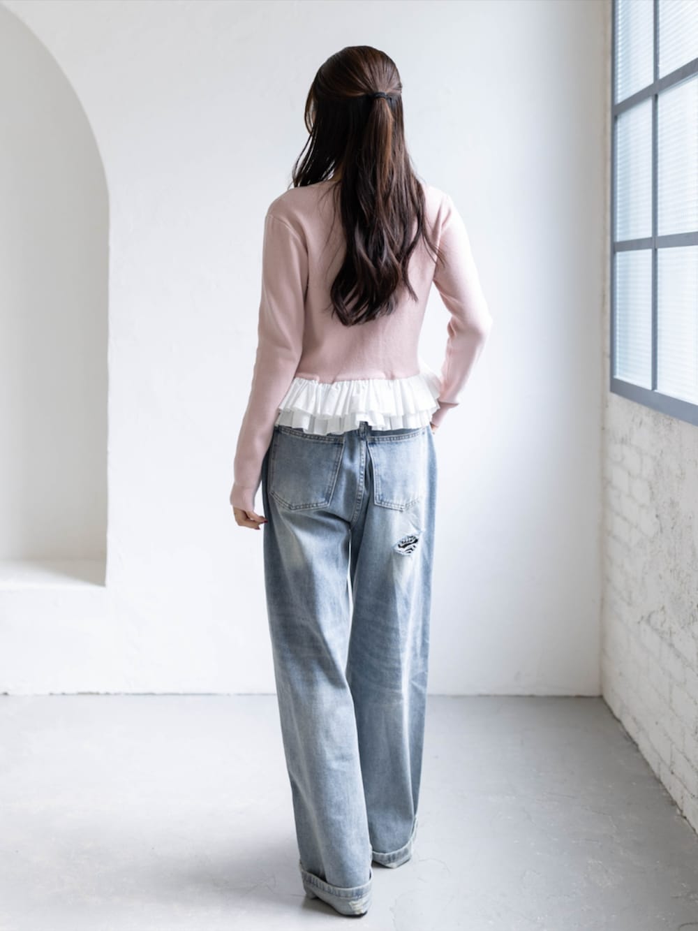 シルバー系のパンプス、ブルー系のデニムパンツ、ピンク系のカーディガン/ボレロを着用したレディースの秋コーディネートの2枚目の写真