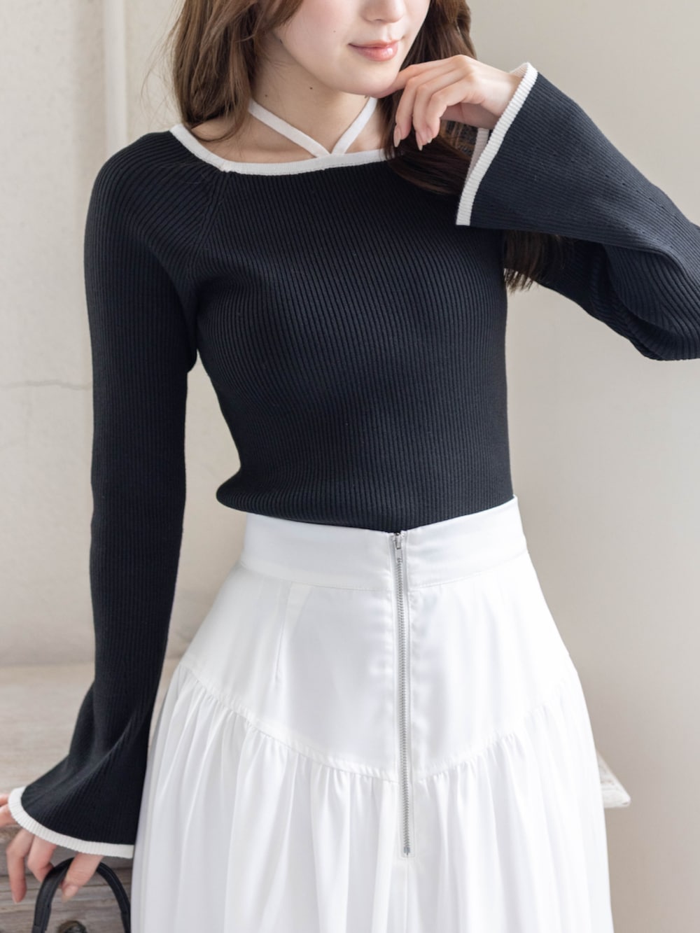 ブラック系のニット/セーター、ホワイト系のスカート、ブラック系のハンドバッグを着用したレディースの春コーディネートの4枚目の写真