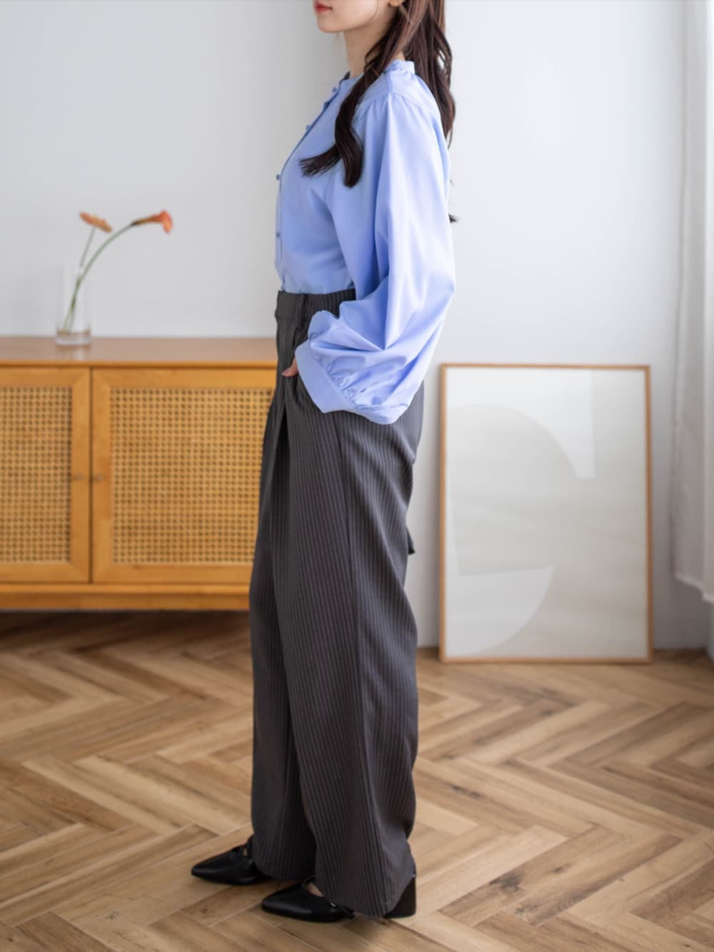 ブラック系のパンプス、ブラック系のハンドバッグ、グレー系のスラックスを着用したレディースの夏コーディネートの2枚目の写真