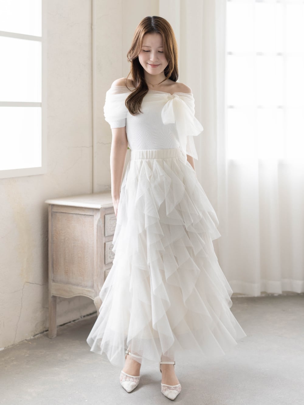 ホワイト系のニット/セーター、ホワイト系のパンプス、ホワイト系のスカートを着用したレディースの春コーディネートの2枚目の写真