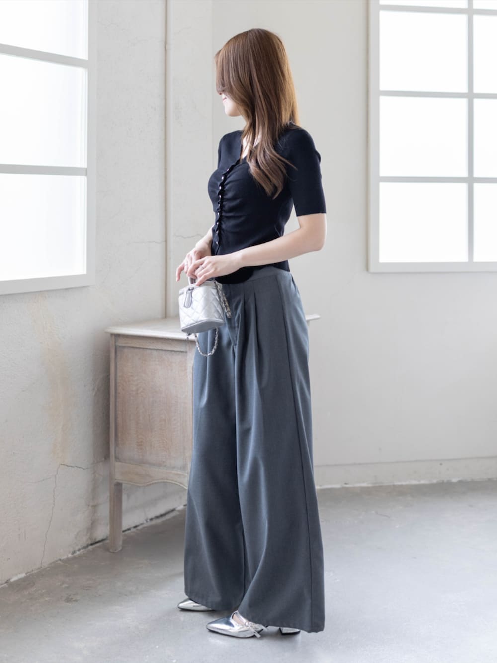 シルバー系のパンプス、グレー系のスラックス、ブラック系のカーディガン/ボレロを着用したレディースの春コーディネートの2枚目の写真