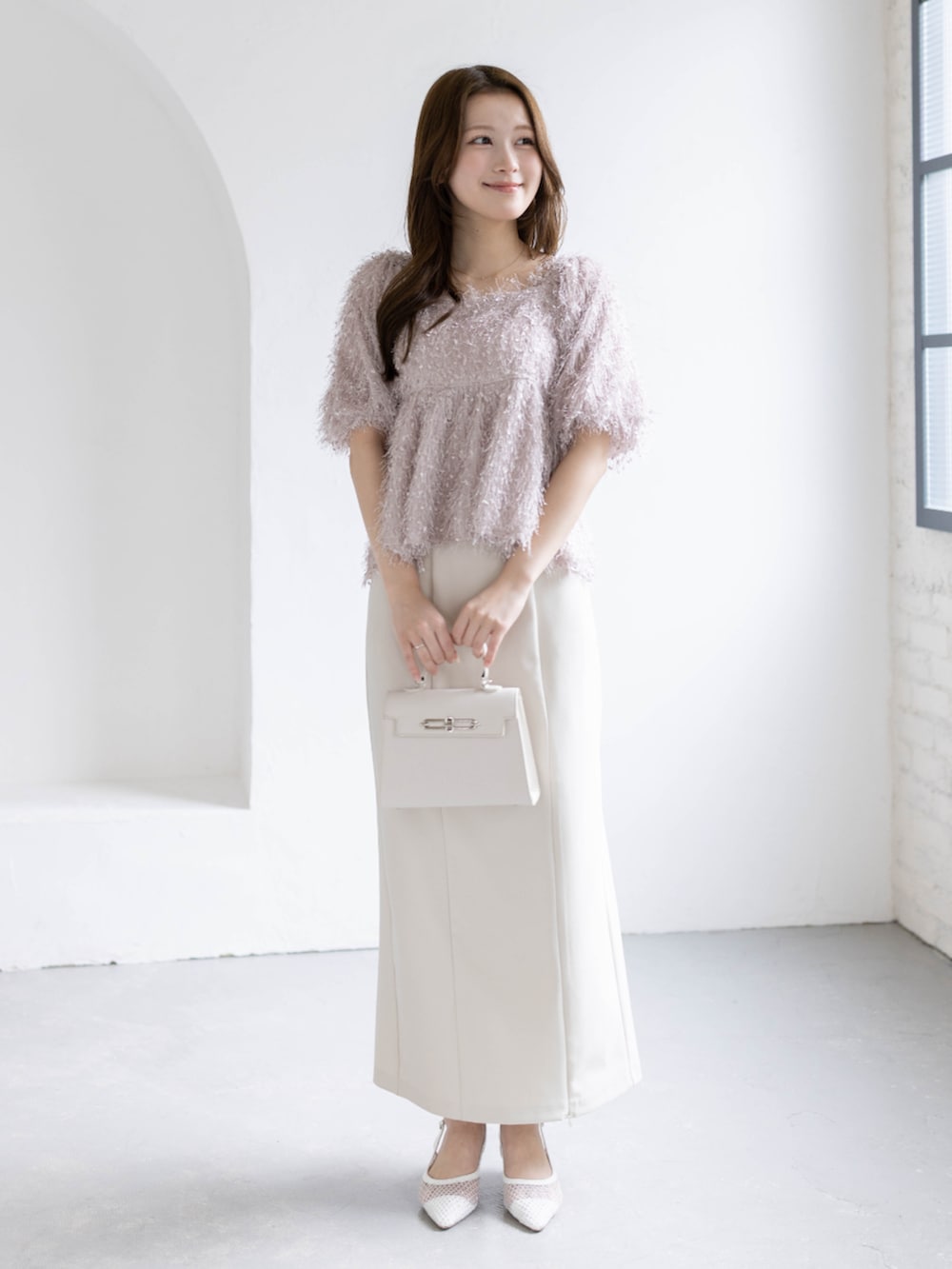 ホワイト系のスカート、ホワイト系のハンドバッグ、ホワイト系のパンプスを着用したレディースの春コーディネートの2枚目の写真