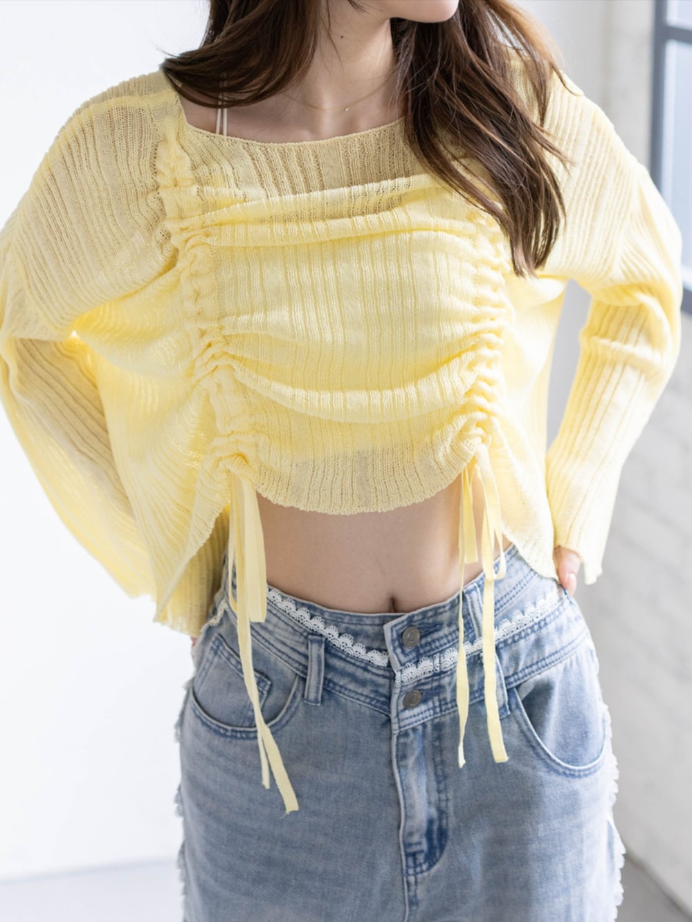 ブルー系のデニムパンツ、ホワイト系のパンプス、イエロー系のニット/セーターを着用したレディースの春コーディネートの5枚目の写真