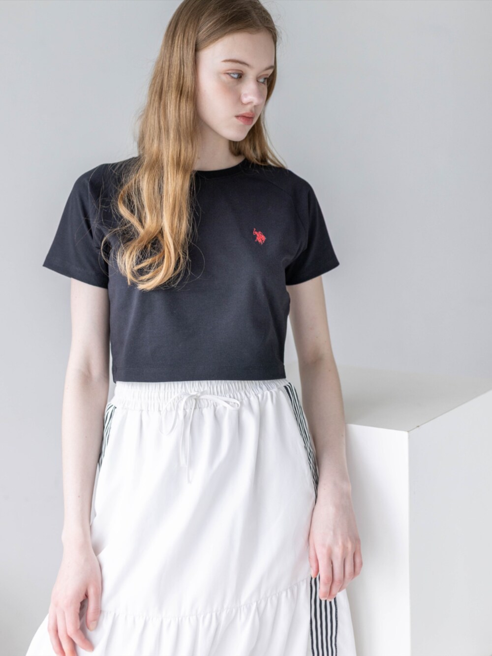 ブラック系のスニーカー、ホワイト系のスカート、ブラック系のTシャツ/カットソーを着用したレディースの夏コーディネートの5枚目の写真