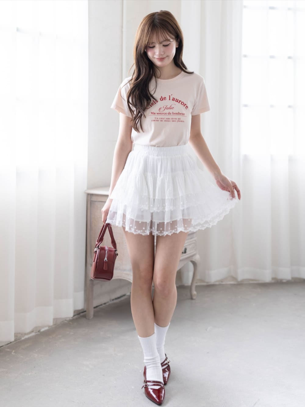 レッド系のパンプス、ピンク系のTシャツ/カットソー、ホワイト系のスカートを着用したレディースの春コーディネートの2枚目の写真