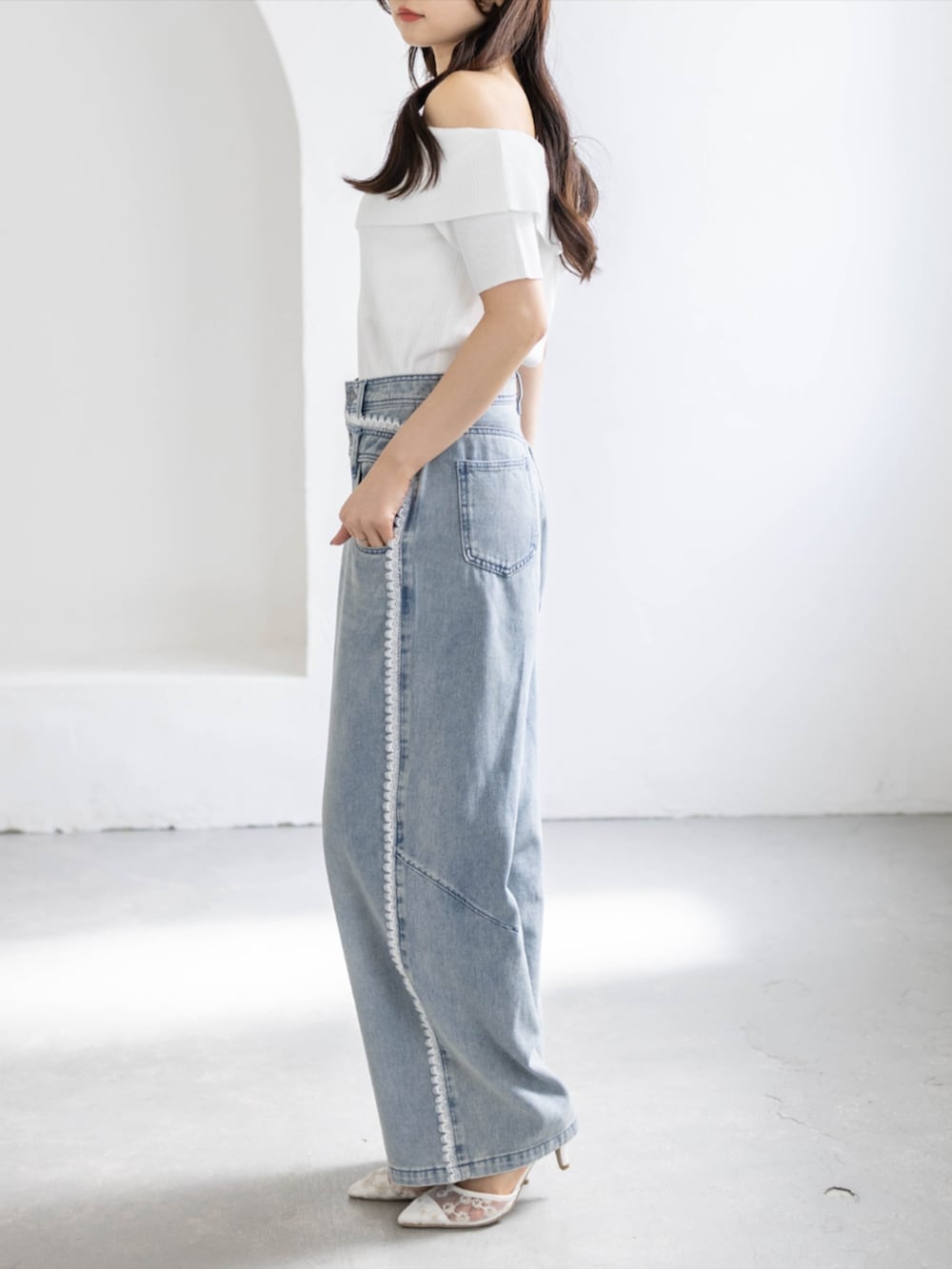 ブルー系のデニムパンツ、ホワイト系のパンプス、ホワイト系のニット/セーターを着用したレディースの春コーディネートの2枚目の写真