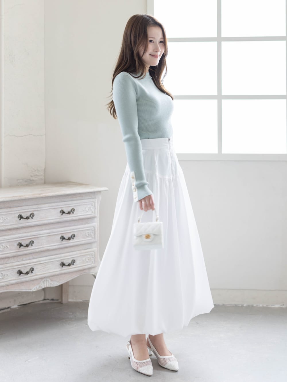 グリーン系のニット/セーター、ホワイト系のスカート、ホワイト系のパンプスを着用したレディースの春コーディネートの2枚目の写真