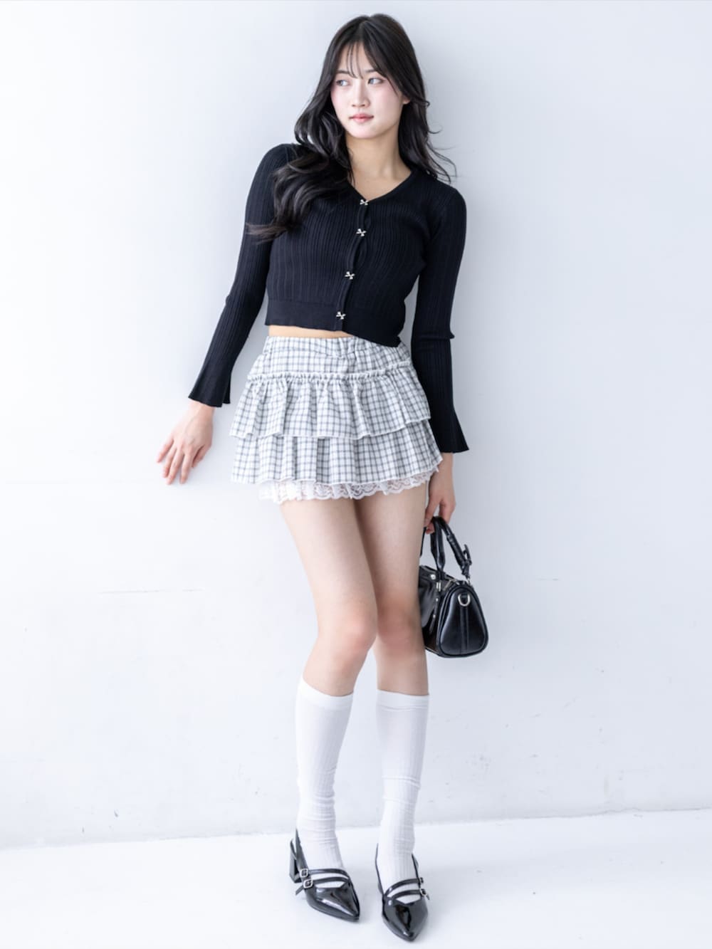 ブラック系のパンプス、ブラック系のハンドバッグ、ホワイト系のスカートを着用したレディースの夏コーディネートの3枚目の写真