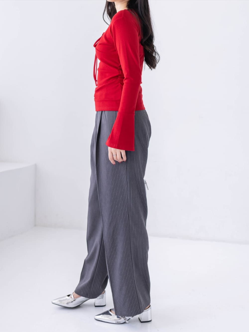 シルバー系のパンプス、グレー系のスラックス、レッド系のTシャツ/カットソーを着用したレディースの春コーディネートの2枚目の写真
