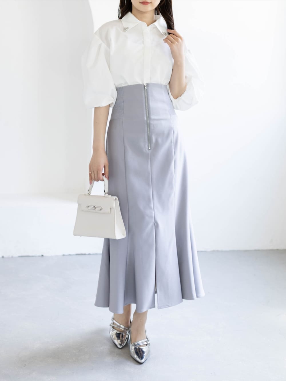 シルバー系のパンプス、ホワイト系のシャツ/ブラウス、グレー系のスカートを着用したレディースの夏コーディネートの3枚目の写真