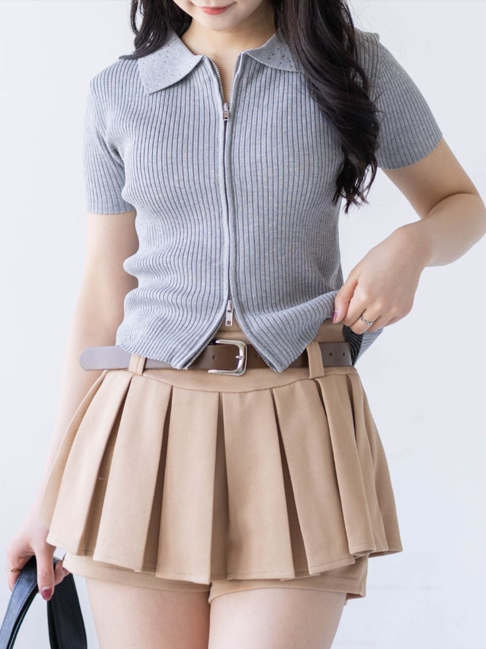 ブラック系のブーツ、ベージュ系のスカート、ブラック系のハンドバッグを着用したレディースの春コーディネートの3枚目の写真