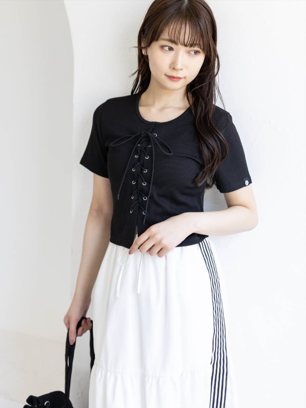 ブラック系のスニーカー、ホワイト系のスカート、ブラック系のTシャツ/カットソーを着用したレディースの夏コーディネートの5枚目の写真