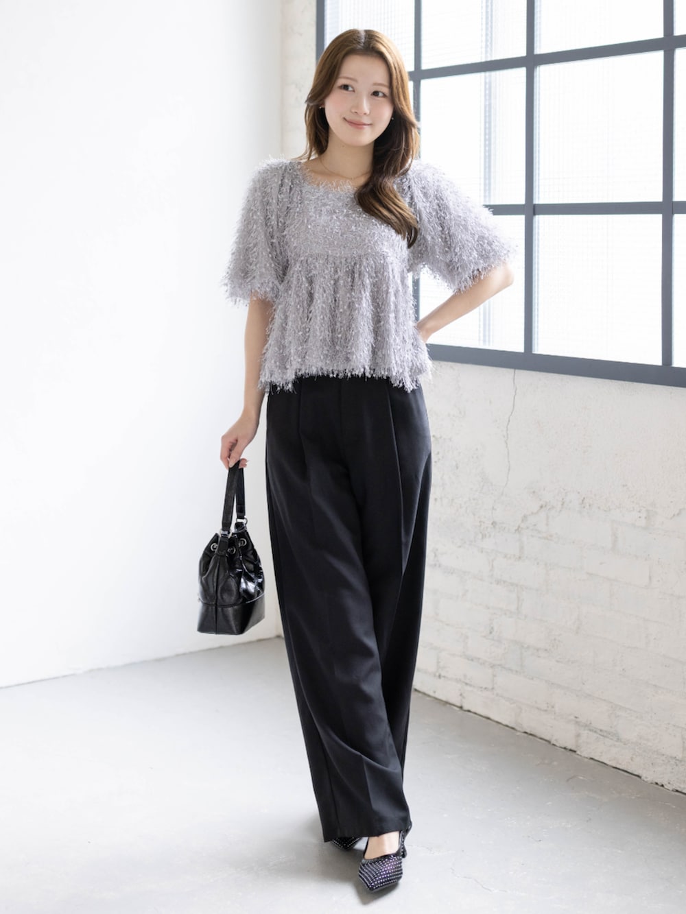 ブラック系のハンドバッグ、ブラック系のパンプス、グレー系のシャツ/ブラウスを着用したレディースの春コーディネートの2枚目の写真