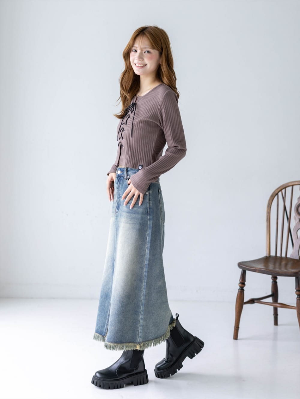 ブルー系のデニムスカート、ブラウン系のTシャツ/カットソー、ブラック系のブーツを着用したレディースの秋コーディネートの3枚目の写真