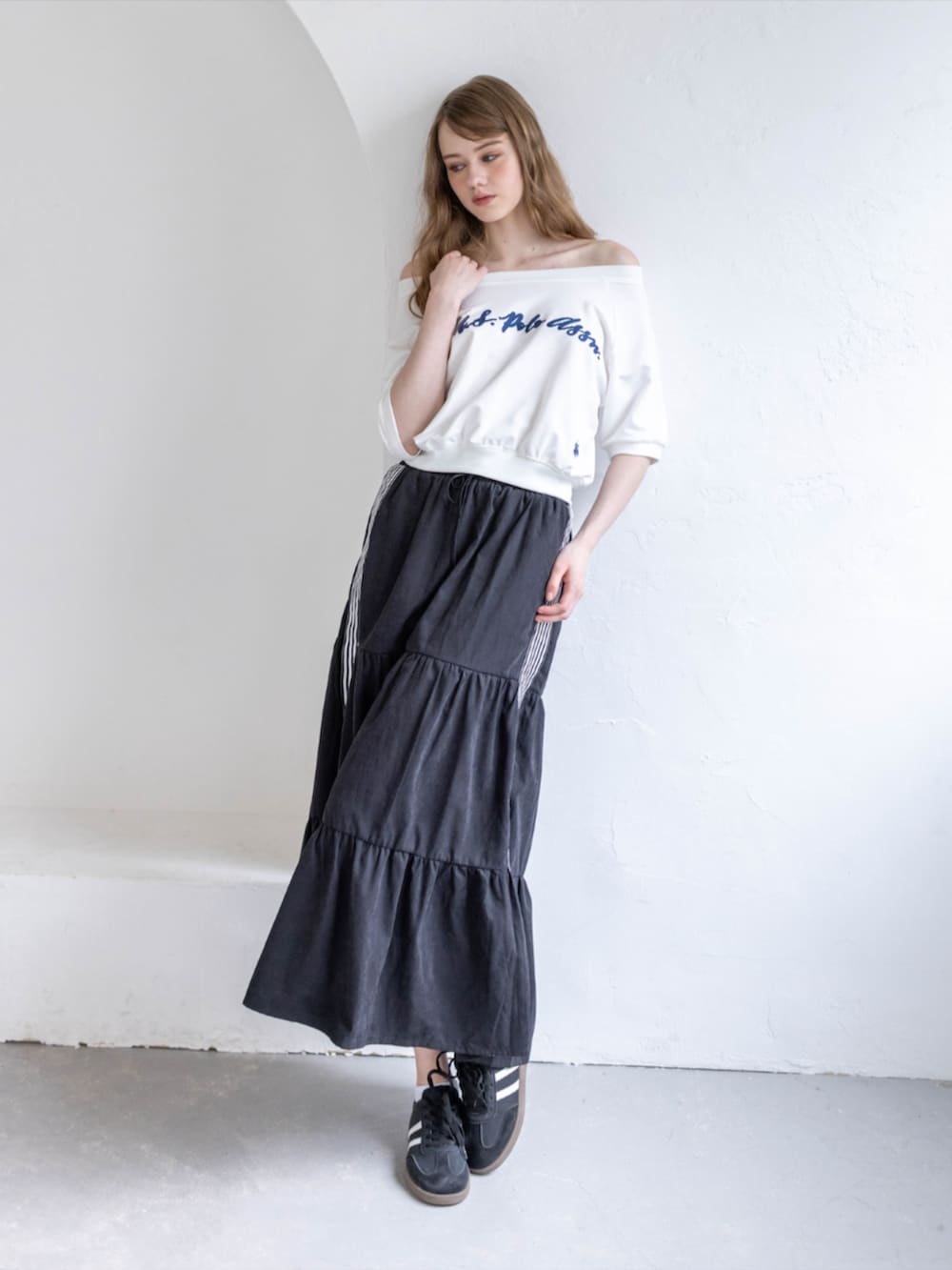 ブラック系のスニーカー、ブラック系のスカート、ホワイト系のTシャツ/カットソーを着用したレディースの夏コーディネートの2枚目の写真