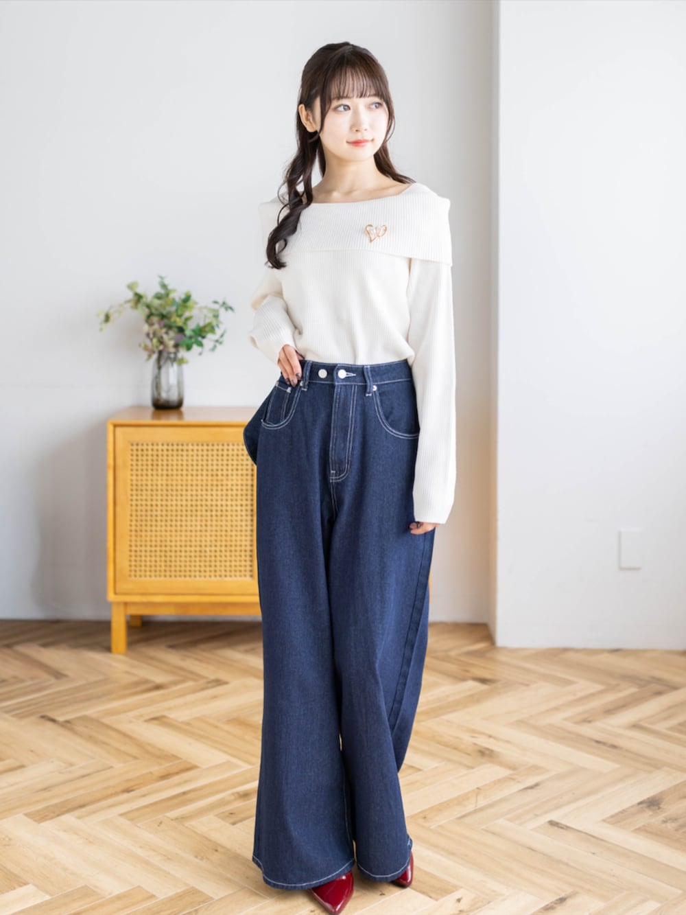 レッド系のパンプス、ブルー系のデニムパンツ、ホワイト系のニット/セーターを着用したレディースの秋コーディネートの2枚目の写真