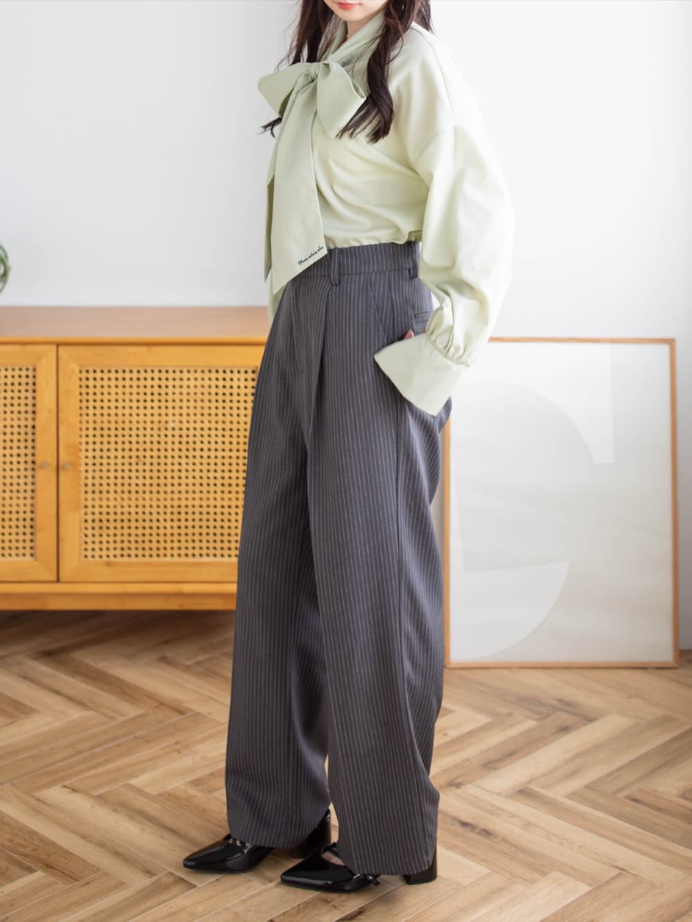 ブラック系のパンプス、グレー系のスラックス、グリーン系のシャツ/ブラウスを着用したレディースの夏コーディネートの3枚目の写真