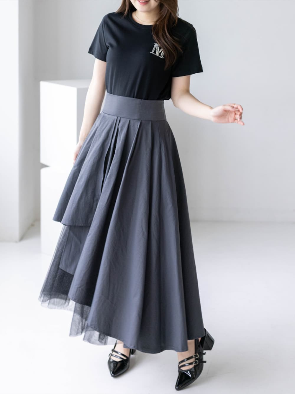 ブラック系のパンプス、グレー系のスカート、ブラック系のTシャツ/カットソーを着用したレディースの夏コーディネートの3枚目の写真