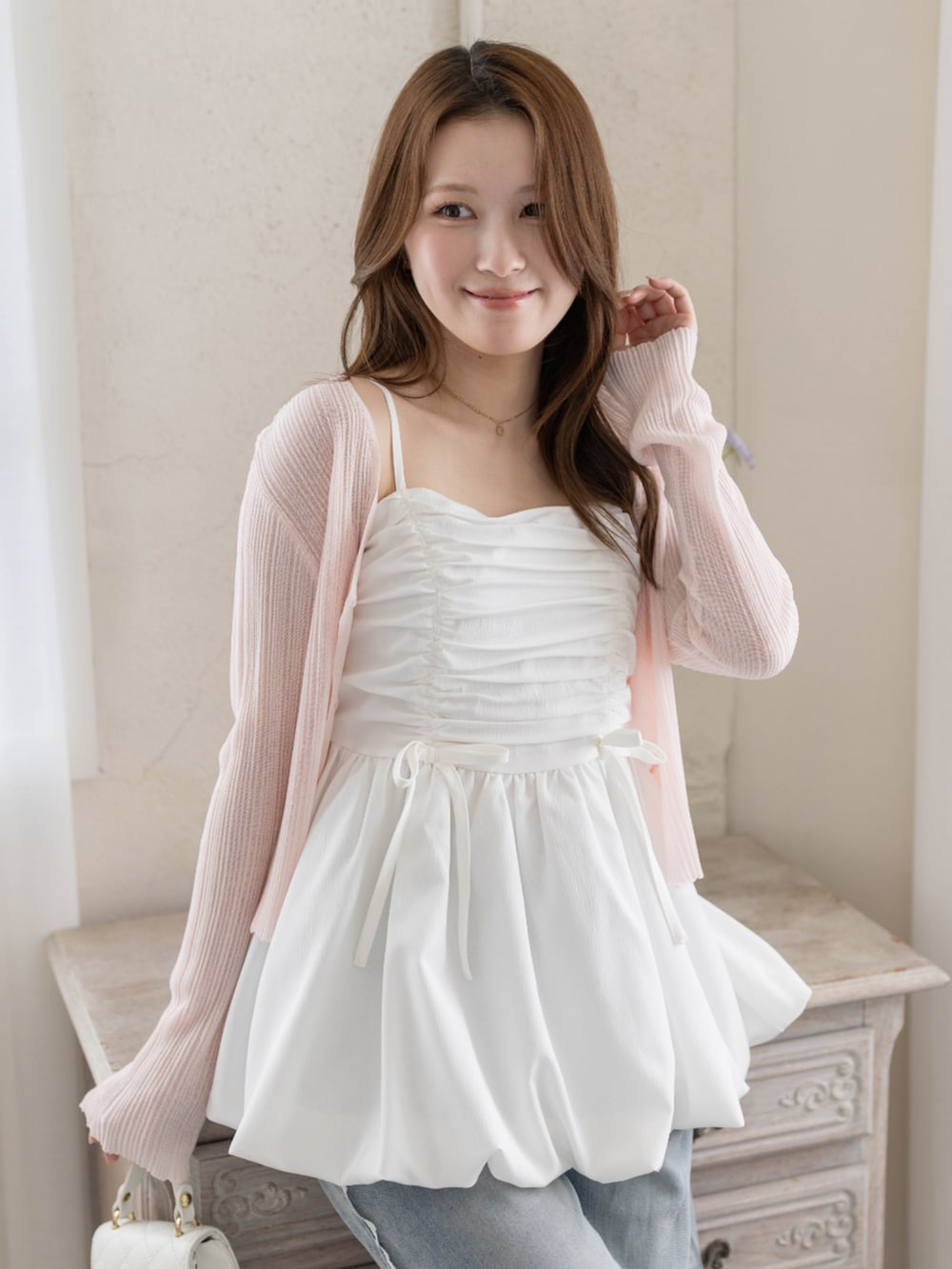 ホワイト系のチュニック、ホワイト系のパンプス、ピンク系のカーディガン/ボレロを着用したレディースの春コーディネートの5枚目の写真