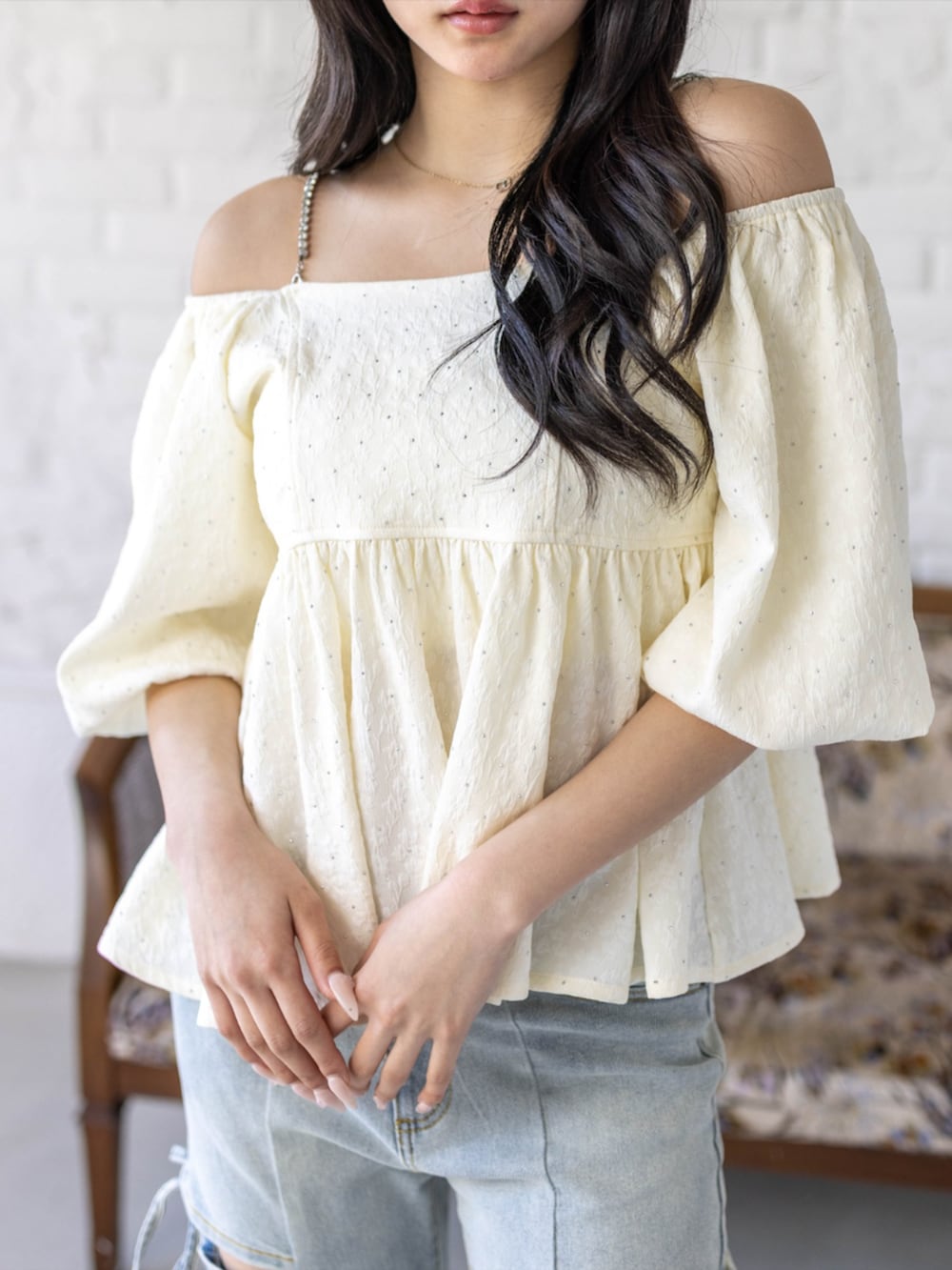 シルバー系のハンドバッグ、ホワイト系のパンプス、ブルー系のデニムパンツを着用したレディースの春コーディネートの5枚目の写真