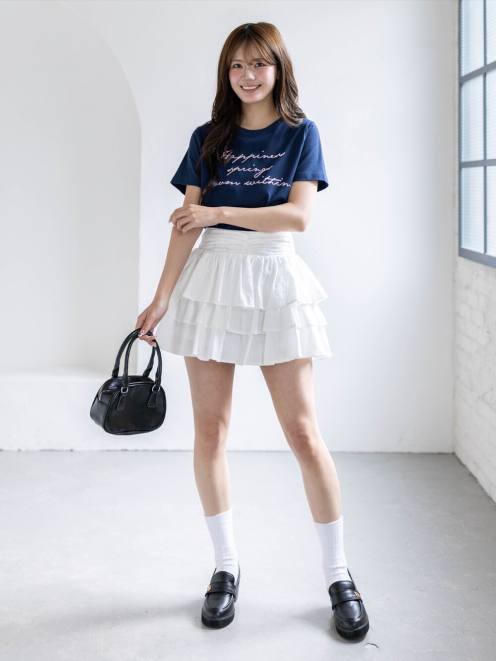 ブラック系のローファー、ホワイト系のスカート、ブルー系のTシャツ/カットソーを着用したレディースの春コーディネートの2枚目の写真