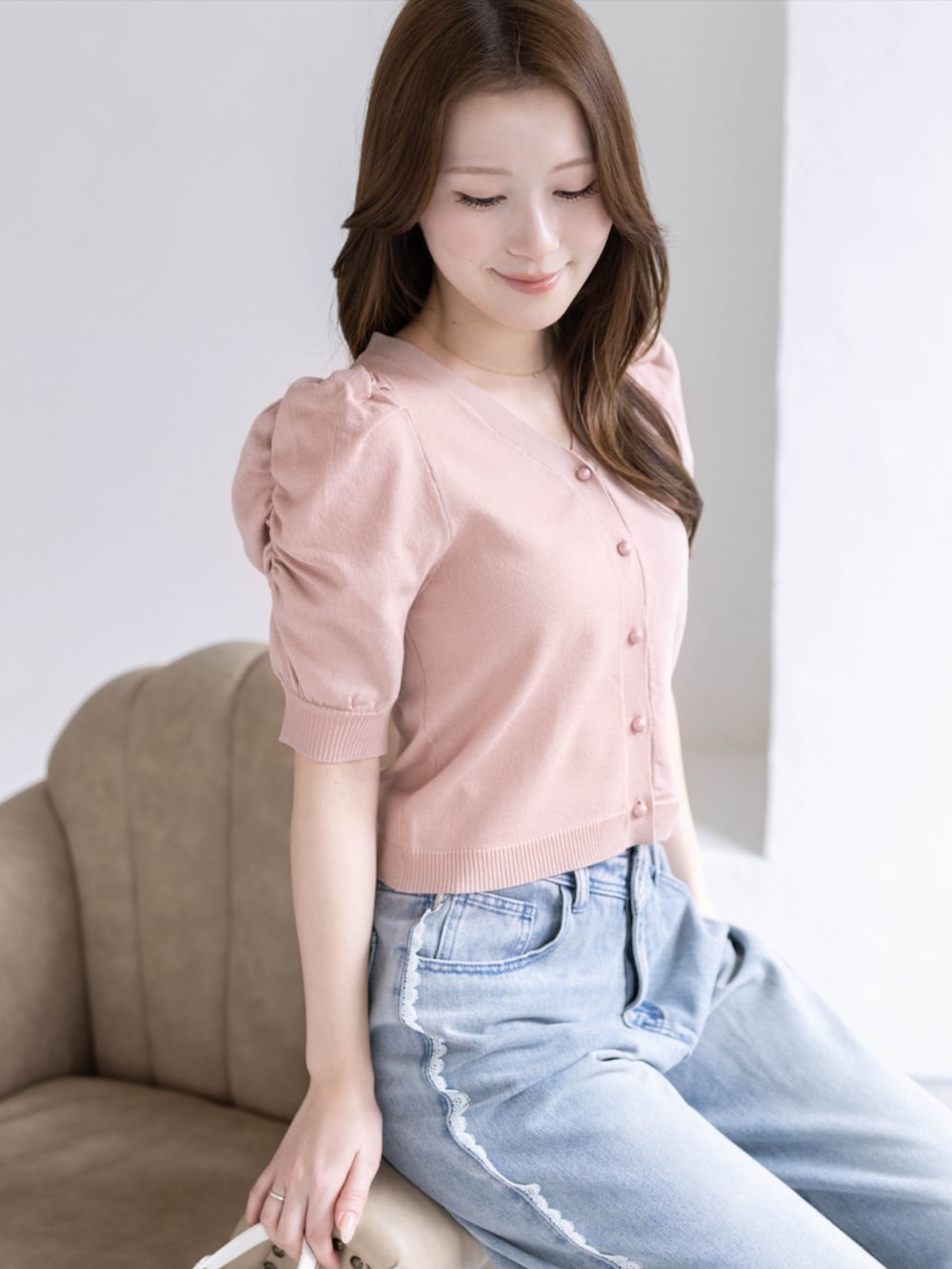 ブルー系のデニムパンツ、ホワイト系のパンプス、ピンク系のカーディガン/ボレロを着用したレディースの春コーディネートの4枚目の写真