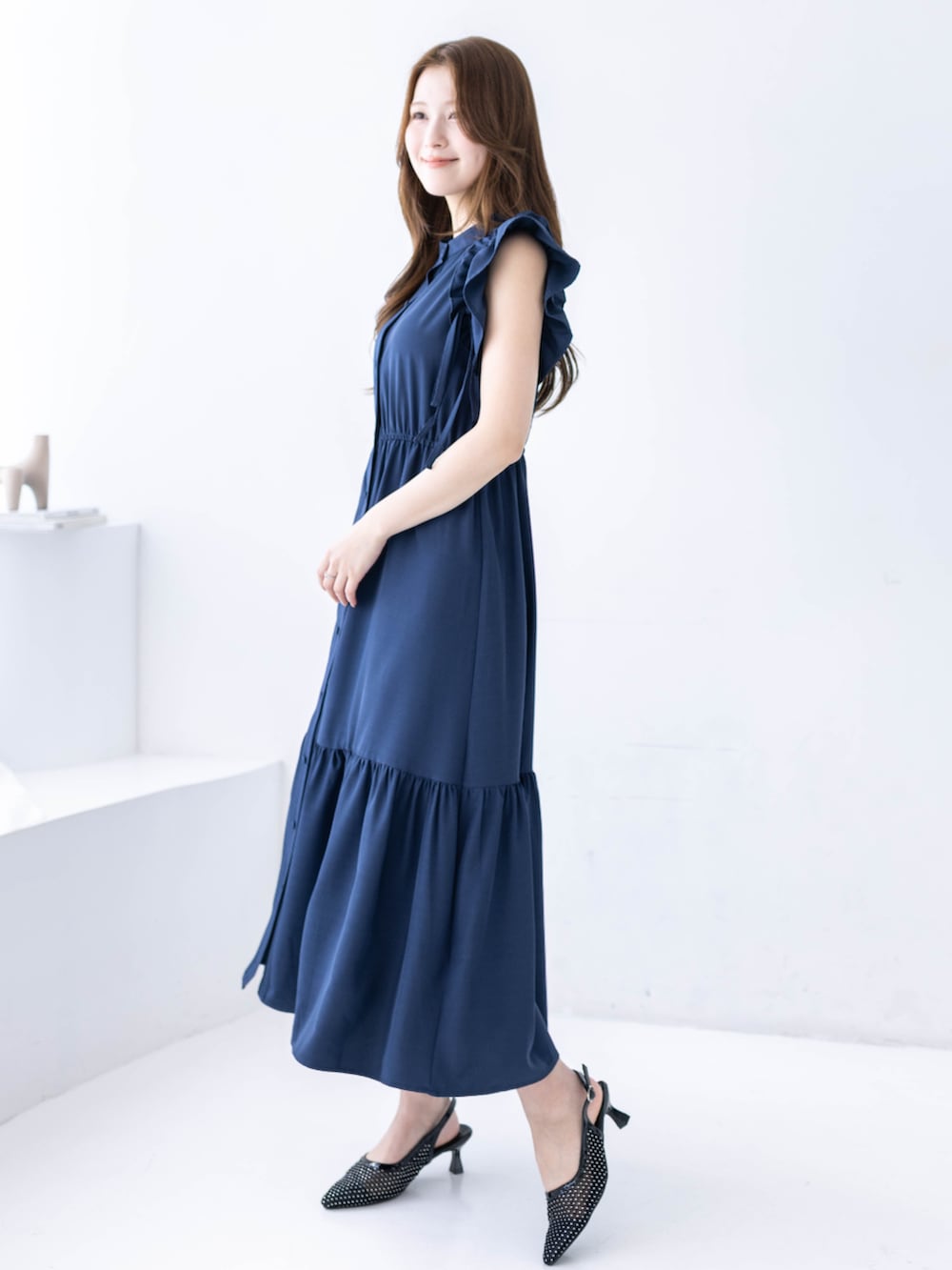 ブラック系のハンドバッグ、ブラック系のパンプス、ブルー系のワンピースを着用したレディースの春コーディネートの2枚目の写真