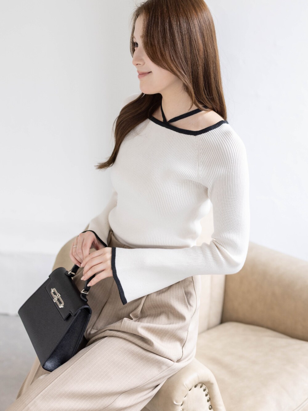 ホワイト系のニット/セーター、ベージュ系のスラックス、ブラック系のハンドバッグを着用したレディースの春コーディネートの6枚目の写真